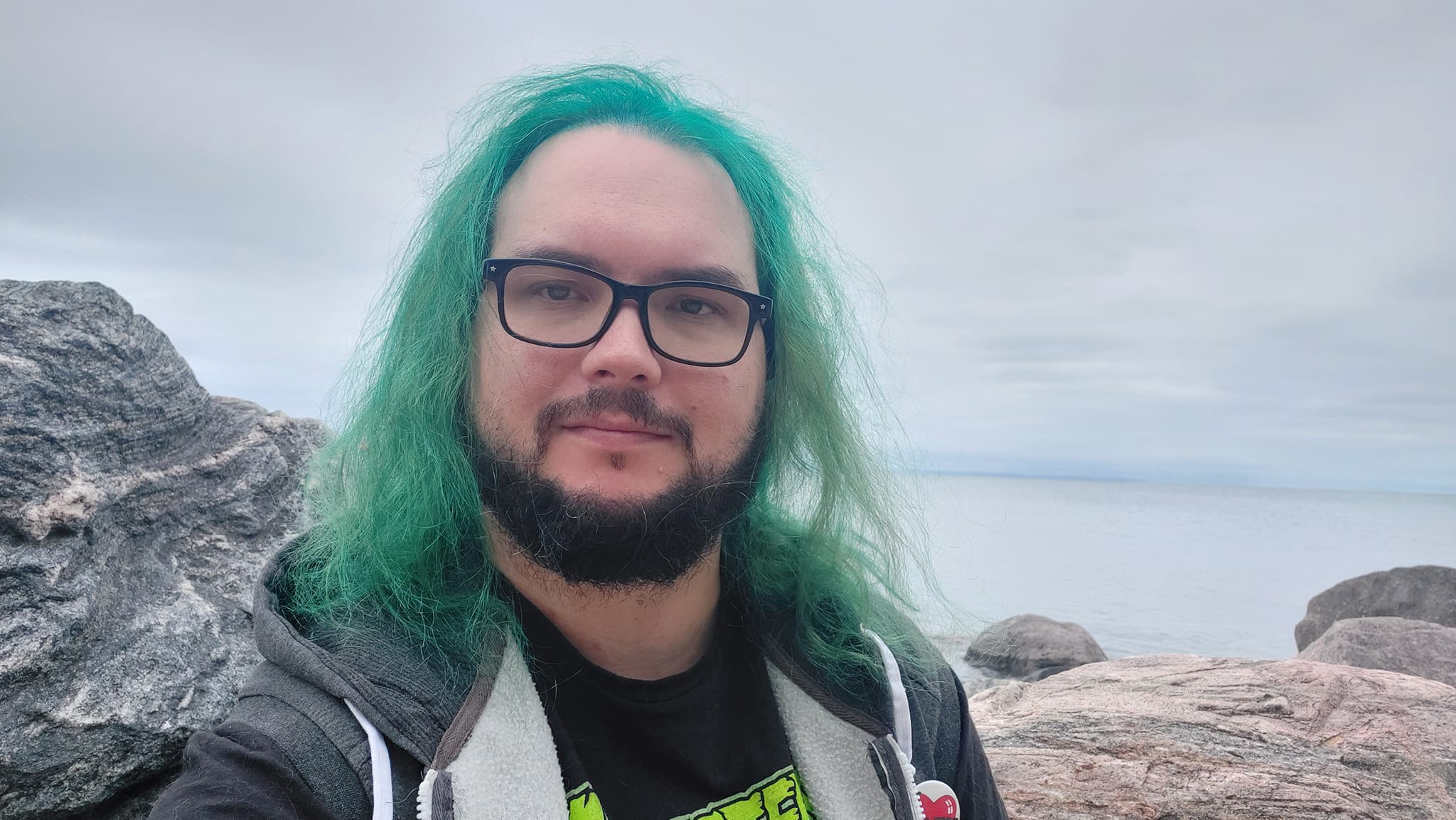 A man with green hair stands outside at a boulder breakwater, photo 17